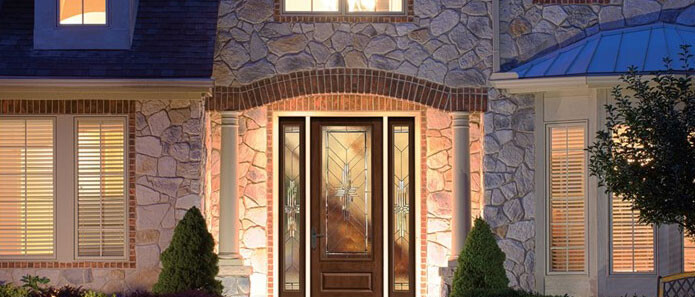 evening view of front of stone house with the lights on inside